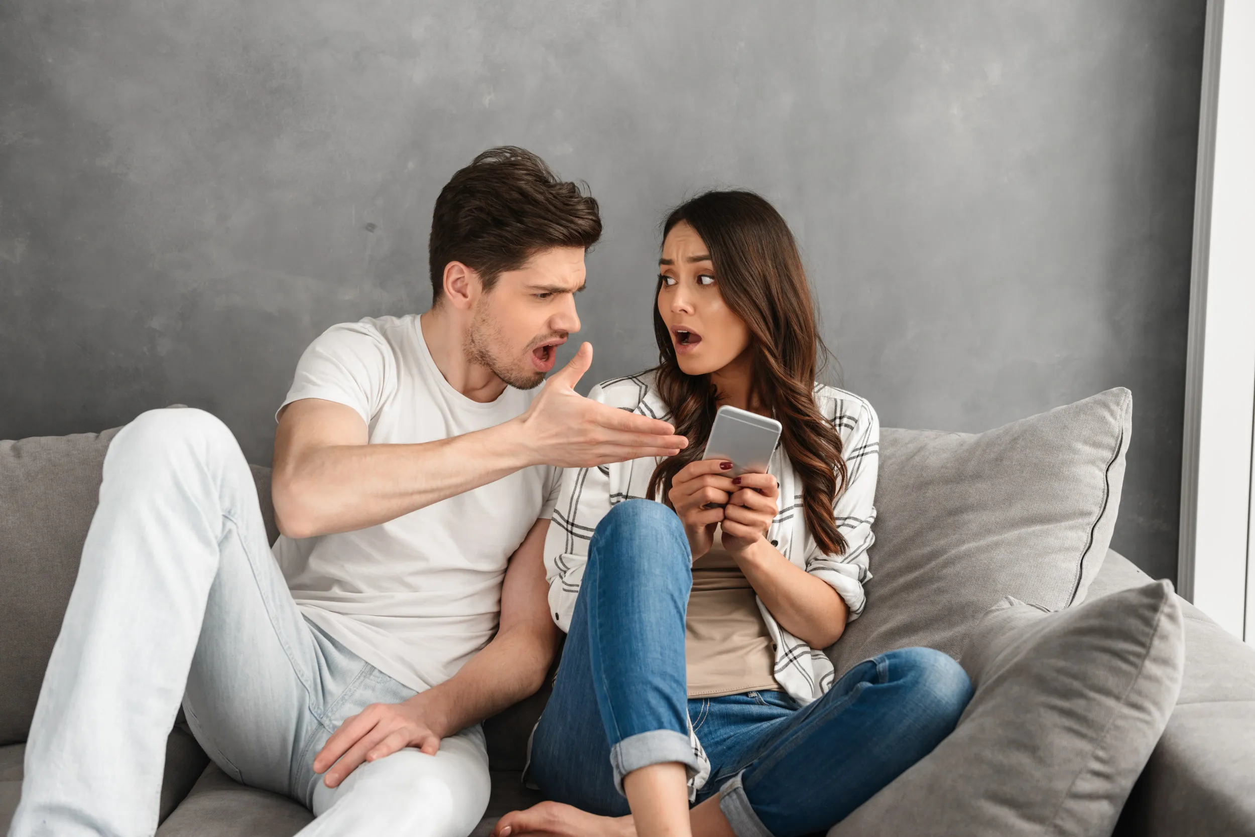 Молодой парень сестру. Woman sitting on Sofa holding smartphone. Sitting together men.